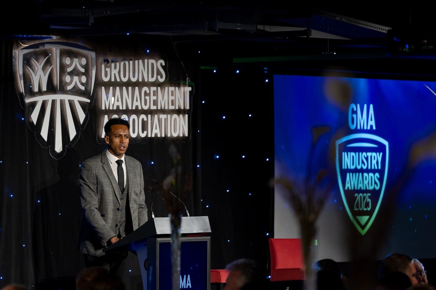 Man speaking at podium during the GMA Industry Awards event.