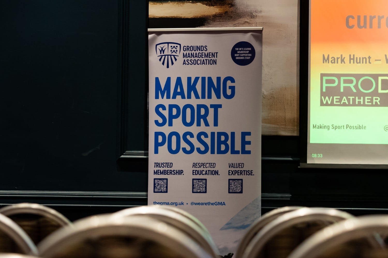 A banner reads "Making Sport Possible" at a sports event with chairs in front.