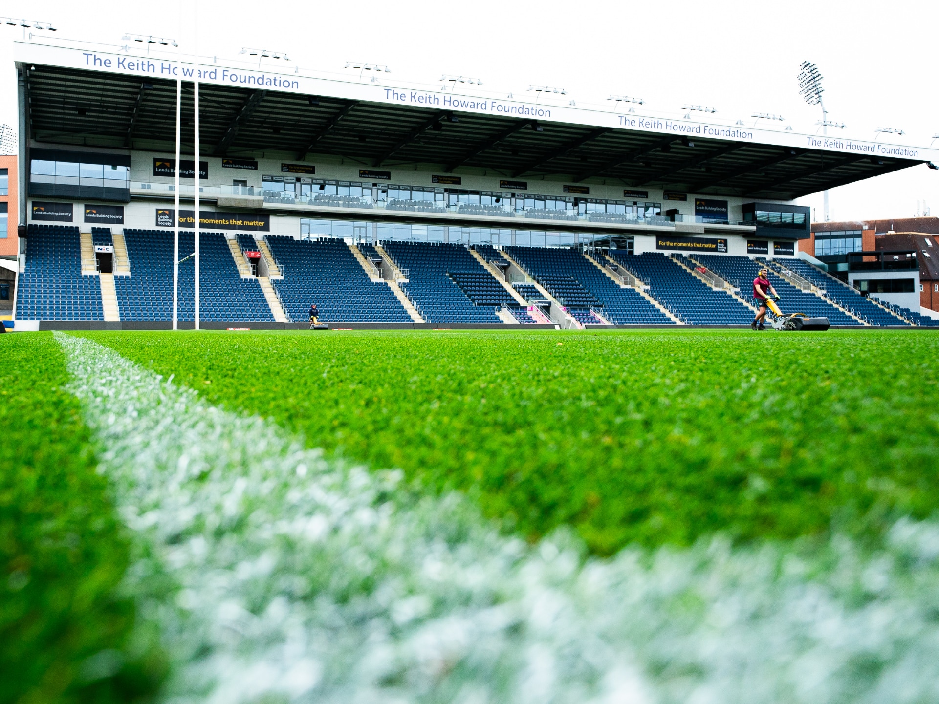 maintenance-funding-rugby A rugby stadium with freshly cut grass and empty blue seats.